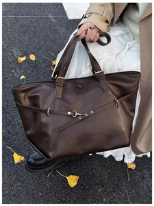 Foto all'aperto di una borsa tote vintage marrone scuro con cinturino e fibbia in metallo