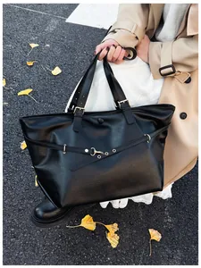 Dettaglio della borsa tote in ecopelle nera con fibbie dorate e texture raffinata
