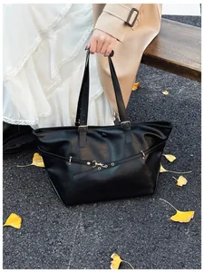 Elegante borsa tote in pelle nera opaca con borchie in una scena autunnale all'aperto