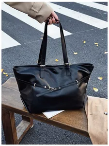 Dettaglio della borsa tote nera con fibbie dorate e scena di moda urbana autunnale