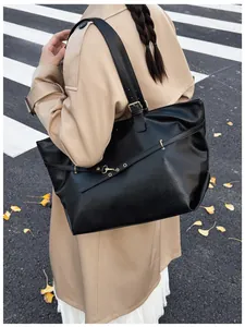Dettaglio di una grande borsa tote in pelle nera con fibbia dorata decorativa sulla tracolla
