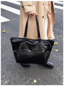 Dettaglio di una grande borsa tote nera in pelle lucida con fibbie metalliche decorative