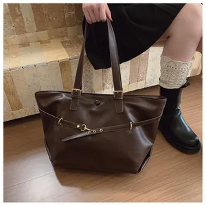 Dettaglio della borsa tote marrone vintage con trama in pelle e fibbie in metallo oro