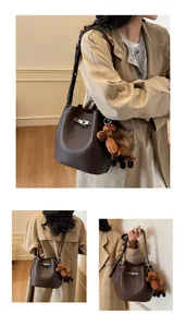 Detail of dark brown lychee leather bucket bag with silver lock and horse charm