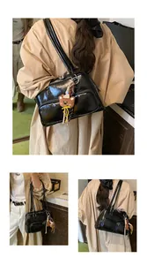 Dettaglio della borsa a spalla nera lucida con due tasche e ciondolo a forma di orsetto