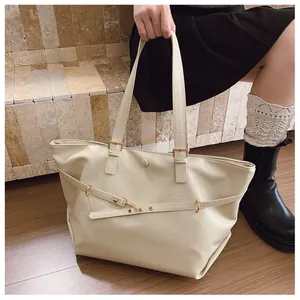 Dettaglio della borsa tote in pelle color crema con finiture dorate e trama strutturata