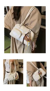 Dettaglio della borsa a spalla in pelle verniciata bianco crema con design multitasca