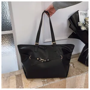 Dettaglio della borsa tote nera con anelli in metallo dorato e trama in pelle