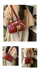 Dettaglio della borsa a spalla rossa lucida con doppie tasche a zip e ciondolo orsetto