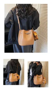 Detail of brown lychee leather bucket bag with silver metal buckle and giraffe charm