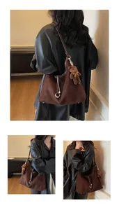 Detail of dark brown suede hobo bag featuring ring hardware and a plush bear charm