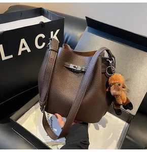 Detail of dark brown leather bucket bag with silver clasp and camel charm in a gift box