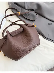 Close-up of brown bucket bag showing pebbled leather texture and gold metal bead detail