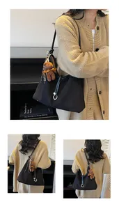 Detail of black suede shoulder bag with bear pendant and silver metal ring hardware