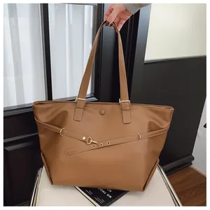 Dettaglio della borsa tote marrone con fibbie metalliche e trama liscia della pelle