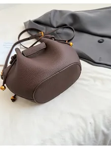 Detailed view of dark brown litchi pattern leather bucket bag with gold metal hardware