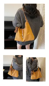 Detail view of mustard yellow suede hobo bag with brown straps and cute bear charm pendant