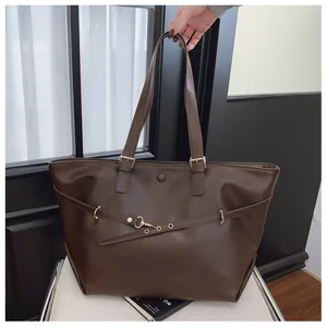 Dettaglio della grande borsa tote marrone scuro con trama in pelle opaca e fibbia dorata