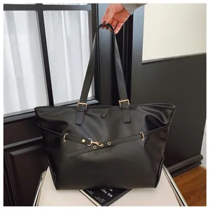 Dettaglio borsa tote nera con fibbie dorate metalliche e trama in pelle martellata