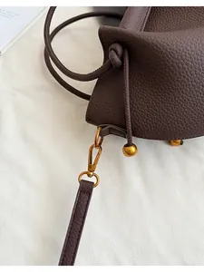 Close-up of dark brown lychee leather texture and matte gold hardware with drawstring knot