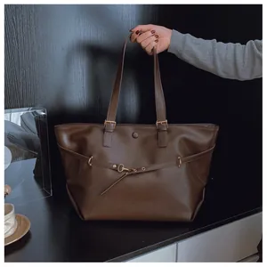 Dettaglio ravvicinato della borsa tote marrone scuro con texture in pelle e fibbia vintage