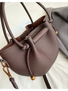 Macro detail of brown lychee grain leather bucket bag with drawstring and gold hardware