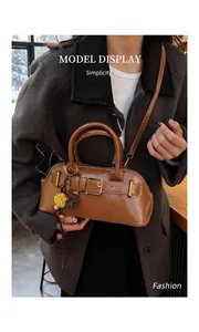 Detail of vintage dark brown shell bag with decorative belt buckle and flower pendant