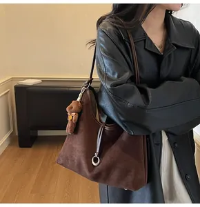 Brown suede hobo bag shown with teddy bear charm and silver metal ring detail