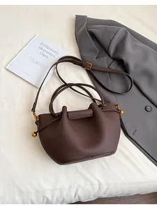 Detail of dark brown lychee texture leather bucket bag with golden ball hardware and drawstring