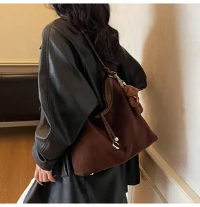 Detail of a large brown suede tote bag with a plush bear charm on a female model