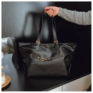 Dettaglio della trama in pelle PU nera opaca e fibbia in oro su una borsa tote grande