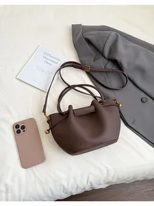 Macro detail of dark brown lychee leather bucket bag with gold ball and drawstring