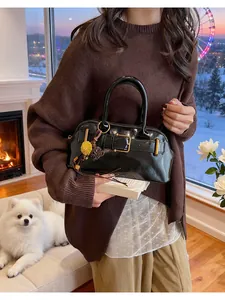 Detail of glossy black patent leather shell bag with golden buckle and floral charm