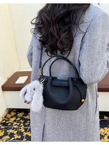 Detail of black pebble leather bucket bag with plush rabbit charm and gold accents