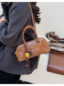 Detail of vintage brown shoulder bag featuring gold buckle and sunflower charm accessory