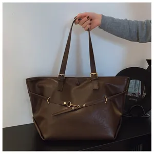 Dettaglio di una borsa tote in ecopelle marrone scuro con fibbia a moschettone dorata