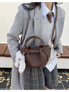 Detail of a brown lychee-patterned bucket bag with a cute plush rabbit charm on the side