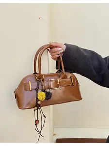 Detail of vintage brown shell handbag with buckle strap and plush decorative pendant