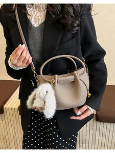 Detail of lychee pattern bucket bag with cute plush rabbit charm and crossbody strap