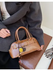 Detail of vintage brown shell bag with leather straps, gold buckles, and fur ball charm