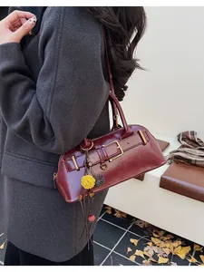 Detail of burgundy vintage shell bag featuring polished faux leather and floral tassel