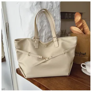 Dettaglio borsa tote beige con grana a buccia d'arancia e fibbie metalliche regolabili