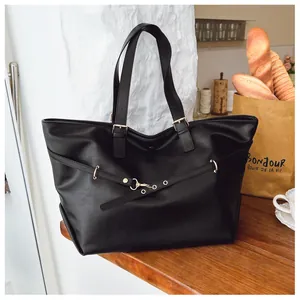 Dettaglio borsa tote in pelle nera con fibbie dorate e cinturini decorativi