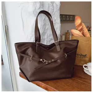 Dettaglio della grande borsa tote marrone scuro con fibbia dorata e cinturini in pelle