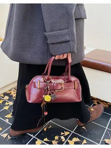 Close-up of retro burgundy leather handbag with decorative buckle and fur pompom charm