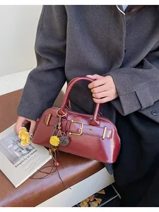 Close-up of deep red leather shell bag with gold buckle and floral tassel detail