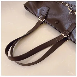 Dettaglio della borsa tote marrone caffè con texture in pelle e fibbie dorate