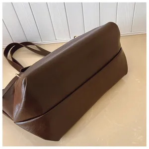 Dettaglio del fondo piatto e della trama laterale di una borsa tote in pelle marrone