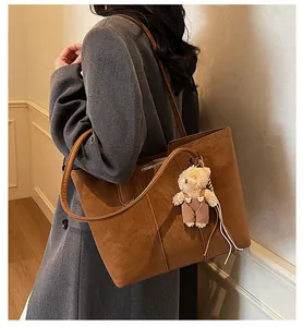 Dettaglio della borsa tote vintage marrone caramello con ciondolo a orsetto