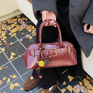Vintage dark red shell handbag with belt buckle and autumn pompom charm on ginkgo leaves